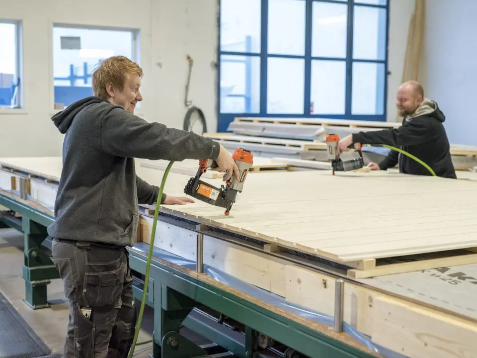 bildet viser to menn som snekrer et element og smiler