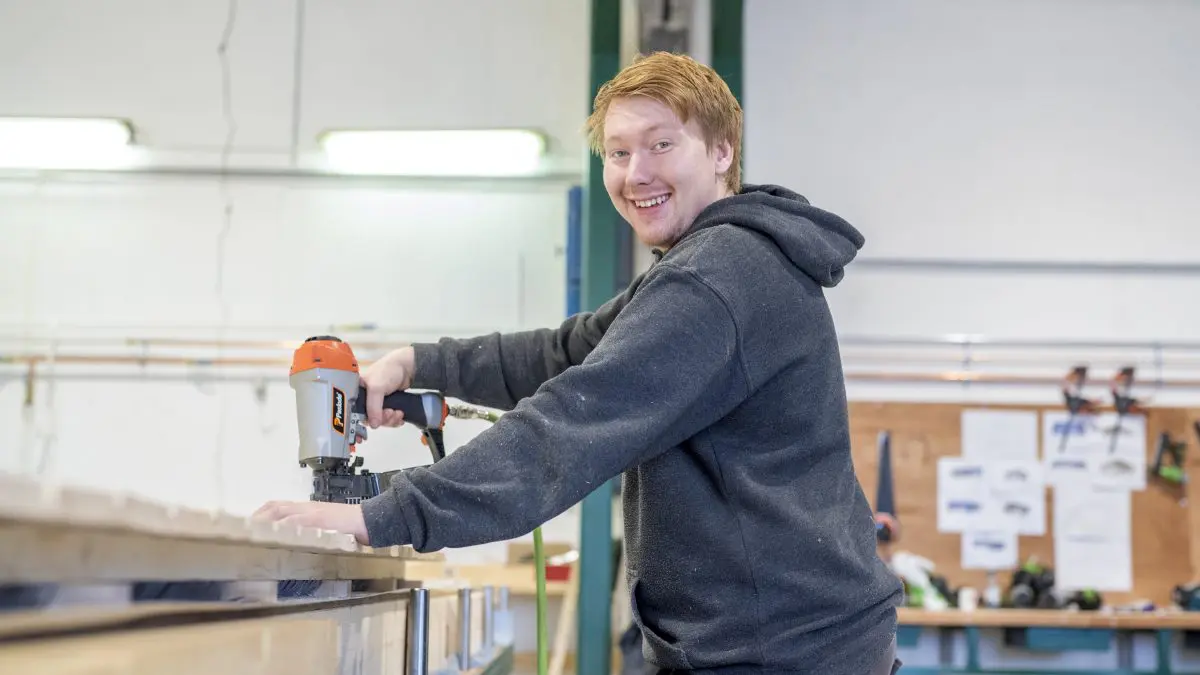 bildet viser en mann som smiler og snekrer