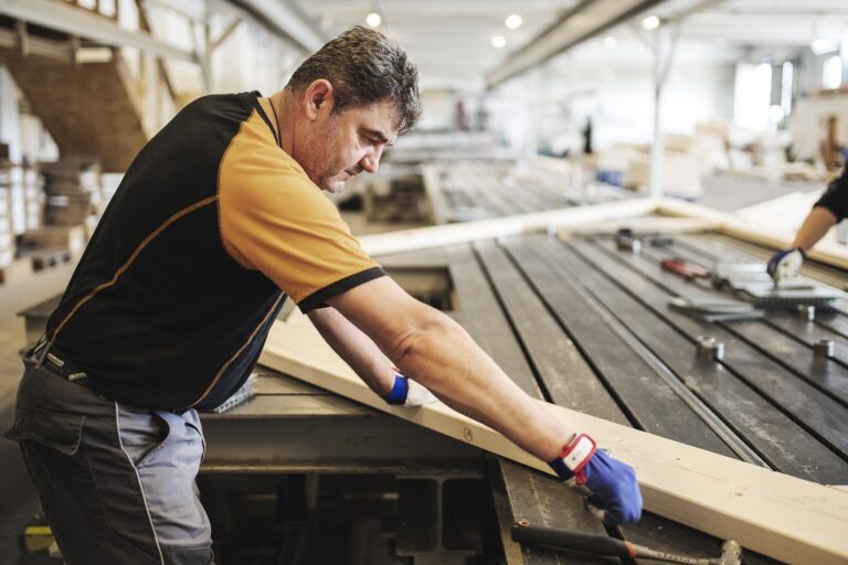 bilden visar en man som arbetar med takstolar i en produktionshall